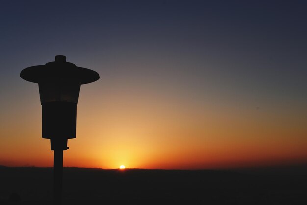 A close-up of Christ the Redeemer statue in Rio de Janeiro, Brazil, during sunset, showing the orange sky, the details of the statue, and the city lights in the background, emphasizing the iconic landmark and its cultural significance.