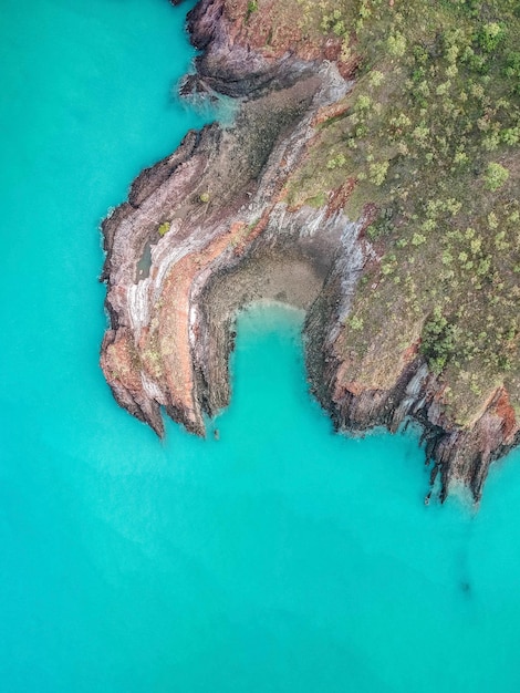 A drone shot of Fernando de Noronha, Brazil, with turquoise waters, dramatic rock formations, and lush green vegetation.