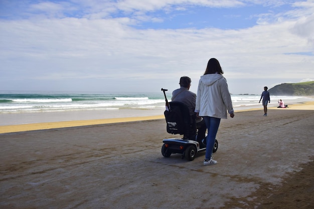 A smiling family with a member in a wheelchair enjoying a day at an accessible beach in Brazil, featuring adaptive beach equipment and accessible walkways.
