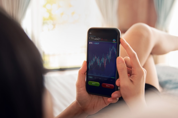 A person using a smartphone app to monitor currency exchange rates, with graphs and charts displayed on the screen. The setting could be a modern, bright café or a co-working space, suggesting ease and accessibility in tracking financial data for travel planning.