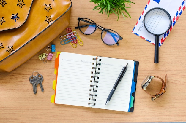 An eye-level shot of a calendar marked with travel dates and circled with a pen, surrounded by travel brochures, a passport, and a pair of sunglasses, symbolizing advance travel planning.