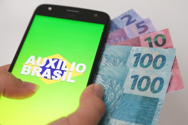 A close-up of a Brazilian real banknote, with a calculator and financial charts in the background, symbolizing financial planning and investment strategy in Brazil.