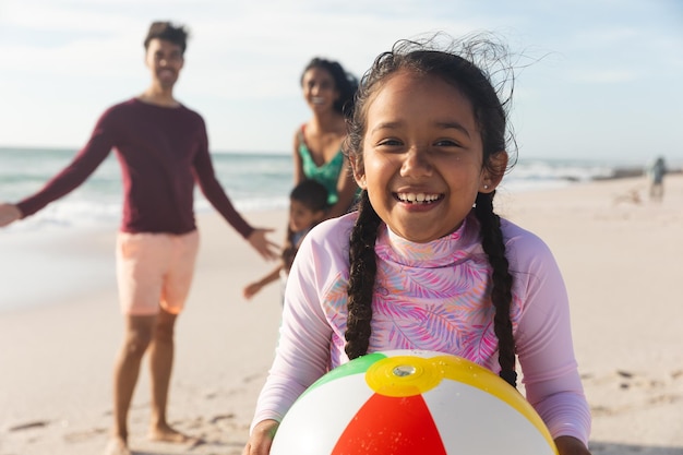 A close-up shot of a Brazilian family enjoying a day at the beach. The sun is setting, casting a warm glow on the scene. They are laughing and playing in the sand, symbolizing the importance of vacations and work-life balance.