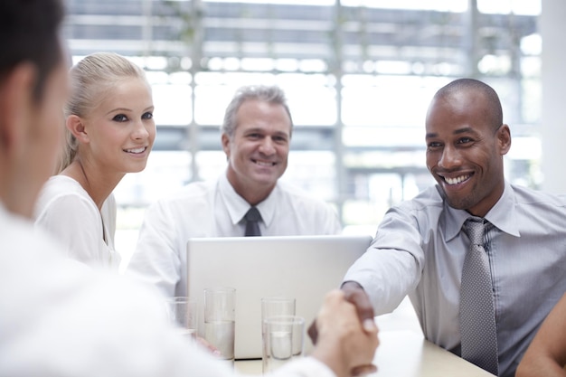 A group of diverse business people shaking hands in a modern office, symbolizing partnerships and foreign investment.