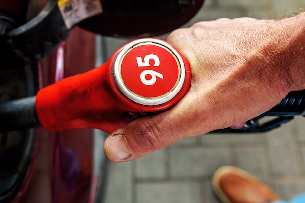 A close-up of a hand holding a gas pump nozzle, with the price display showing a lower amount than usual. The focus is on the numbers, emphasizing the savings for the consumer.