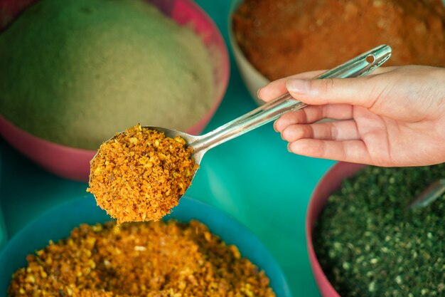 Close-up shot of a spice seller's hands scooping spices, capturing the textures and colors of the Brazilian spice products.