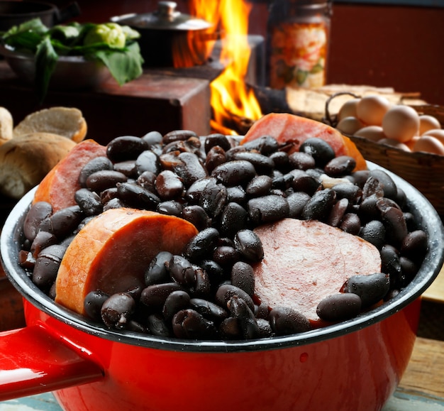 A close-up shot of a pot of simmering feijoada, with various cuts of meat and spices visible, evoking a sense of warmth and hearty flavors.