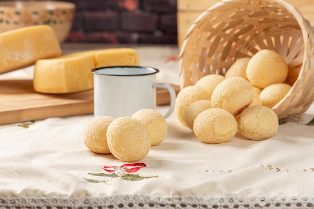 A photo showcasing a variety of homemade pão de queijo in different sizes and shapes, some golden brown and freshly baked, others still frozen, with visible ice crystals on the surface. The arrangement shows the process from dough to baked product, with some pão de queijo displayed in clear freezer bags labeled with the date. The backdrop includes common kitchen tools and ingredients used in the recipe.