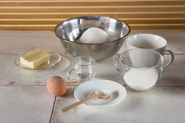 Close-up shot of the ingredients needed for the creamy cornmeal cake recipe, arranged on a kitchen counter: cornmeal, eggs, milk, sugar, oil, and baking powder.