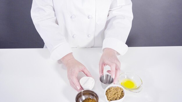 A top-down view of a chef meticulously weighing and measuring out ingredients in a professional kitchen setting. Focus on the precise tools and attention to detail, with a variety of colorful, fresh vegetables and spices surrounding the chef.