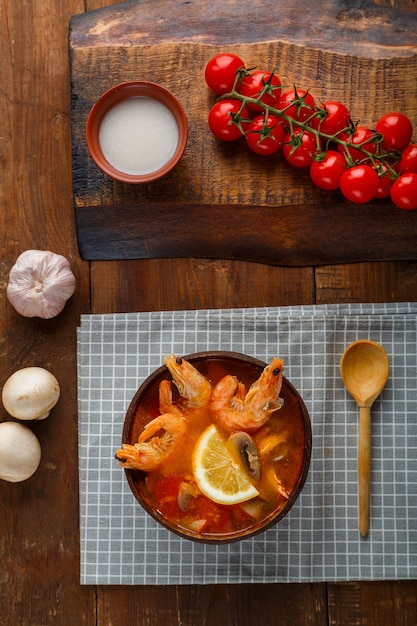 A medium shot of a table setting with a freshly prepared Moqueca Capixaba in a clay pot, accompanied by bowls of steaming white rice, a side of pirão, and a colorful green salad. The focus is on the presentation and the inviting nature of the meal.