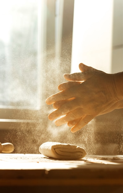Close-up shot of hands kneading dough on a floured surface, with a warm, inviting light. The focus is on the texture of the dough and the artisan skill involved in baking.
