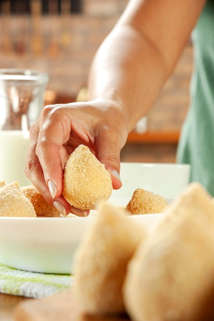 A close up of a vegan coxinha being prepared. The filling is made of jackfruit and spices, and the outer dough is golden brown and crispy. A cook's hands are visible, shaping the coxinha.
