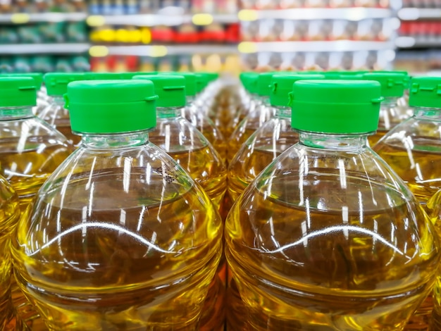 A close-up shot of various olive oil bottles on a supermarket shelf, with focus on the price tags showing the recent increase.
