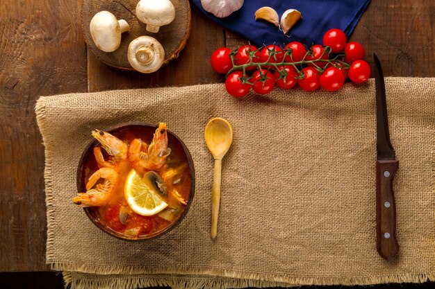 A top-down view of a Brazilian moqueca dish being prepared with various ingredients like fish, tomatoes, peppers, and coconut oil being poured in.