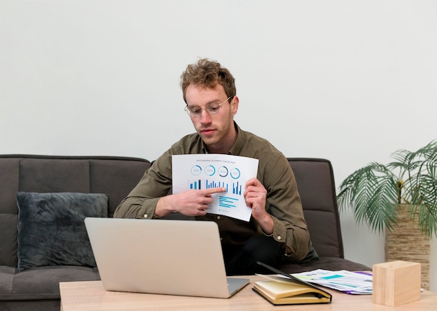 Image of a person working on a laptop at home, overlaid with charts showing rising inflation and debt levels. The overall feel should be one of concern and economic hardship.