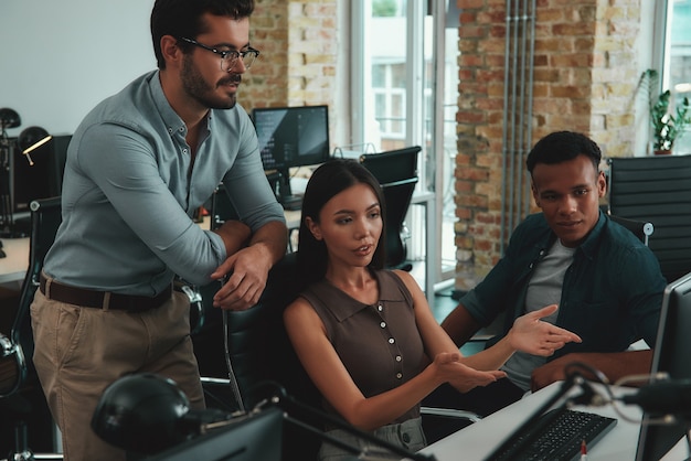 A diverse team of IT professionals collaborating on a project in a modern office in São Paulo, Brazil. Laptops, monitors, and whiteboards filled with code and diagrams illustrate the high-tech nature of their work.
