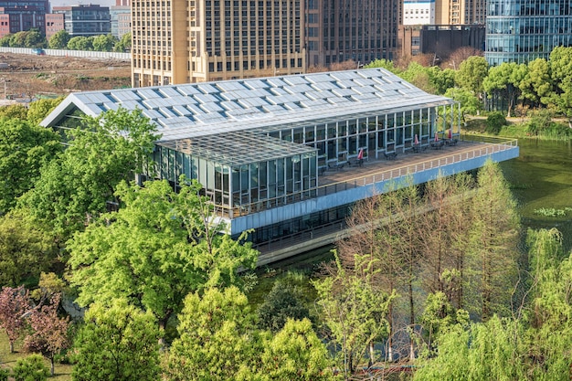 A green building with solar panels on the roof, surrounded by lush greenery, symbolizing sustainable business practices and environmental responsibility.