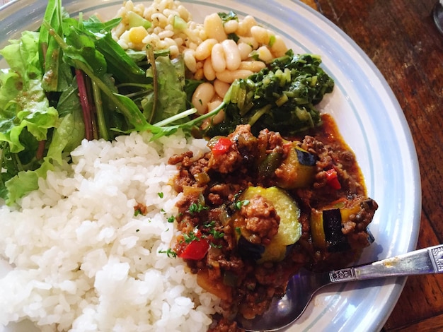 A perfectly plated feijoada with separate bowls of rice, collard greens, farofa, orange slices, and a small dish of hot sauce. The feijoada is served in a deep bowl, highlighting the stew's thickness and the variety of ingredients. The presentation is clean and appetizing.