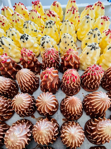 A vibrant display of various brigadeiro flavors on a dessert table, including classic chocolate, white chocolate with sprinkles, and peanut butter. Each brigadeiro is neatly arranged and garnished differently.